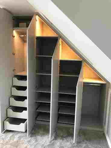 Stylish under-stairs fitted wardrobe in Romfors with illuminated shelves, drawers, and a sleek design for maximizing space and organization.