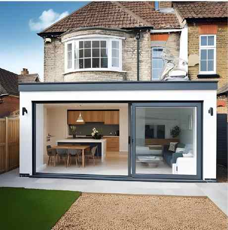 Modern home extension in Romford featuring large glass sliding doors, revealing a stylish dining area and living space, with a green lawn outside.