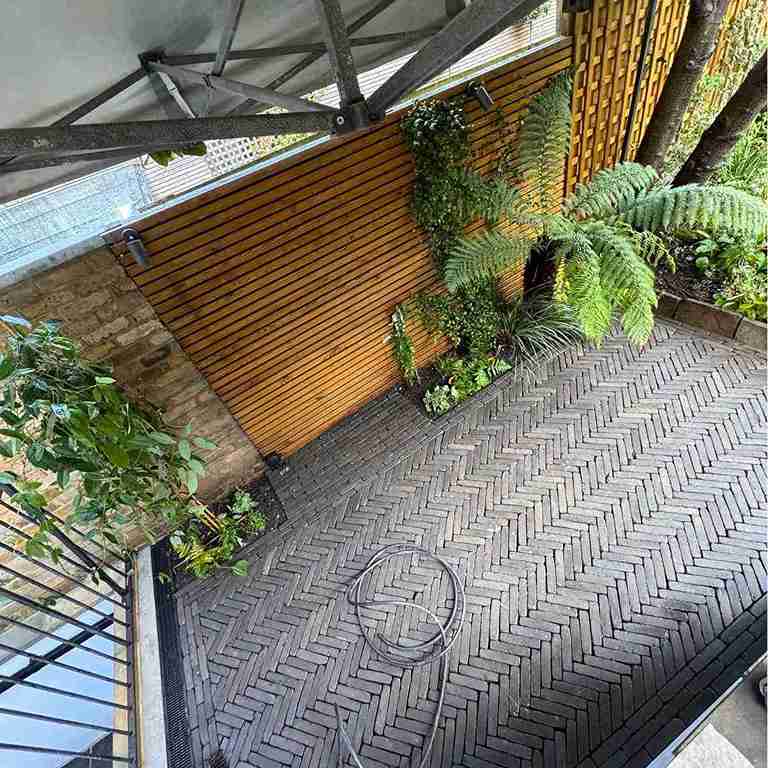 Fence installation with herringbone brick paving, lush plants, and a wooden fence wall in a garden in Romford.