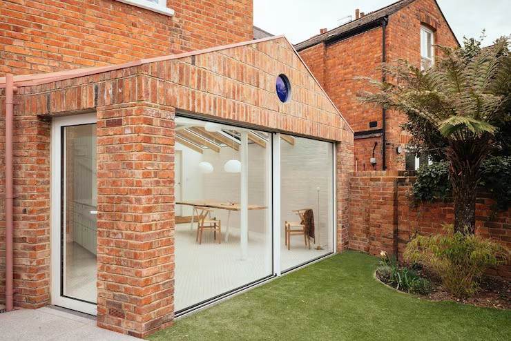 Modern brick home extension in Romford with full-height glass doors, opening to a bright interior and landscaped garden.